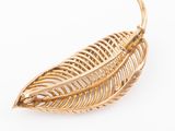 a close up of a gold leaf brooch on a white background