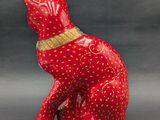 a red cat figurine sitting on a gray surface