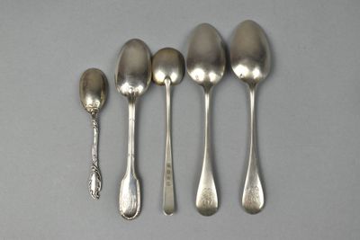 six spoons and a spoon rest on a table