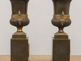 pair of antique bronze vases on pedestals on a table