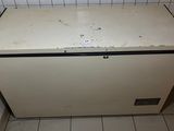 a small white refrigerator in the corner of a tiled room