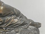 a statue of a woman laying down on a rock
