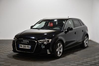 Une Audi noire est garée dans une pièce au sol carrelé en damier.