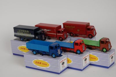plusieurs camions jouets sont alignés sur une surface blanche