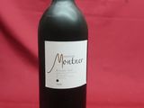 the bottle of red wine is sitting on a red cloth