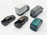 six toy cars and a truck on a white surface