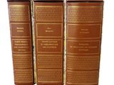 three brown books sitting on top of each other on a white surface