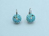 a pair of turquoise and white earrings on a light blue background
