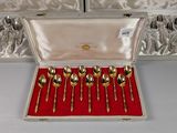 six silver spoons in a case on a table