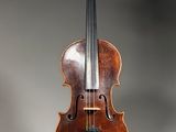 un vieux violon posé sur un pupitre, sur fond gris