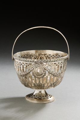 an antique silver basket with a handle on a white surface