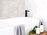 une baignoire blanche posée à côté d'un tabouret en bois dans une salle de bains