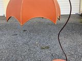 an orange umbrella that is on a metal stand