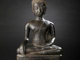 an image of a bronze statue of a person sitting on top of a pile of books