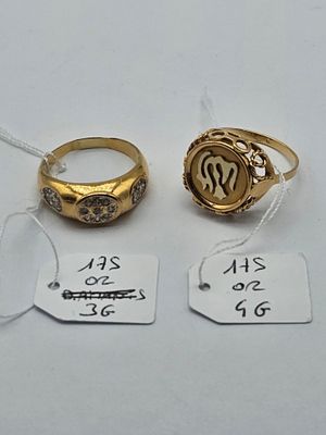 two gold rings and a silver ring are on a white table