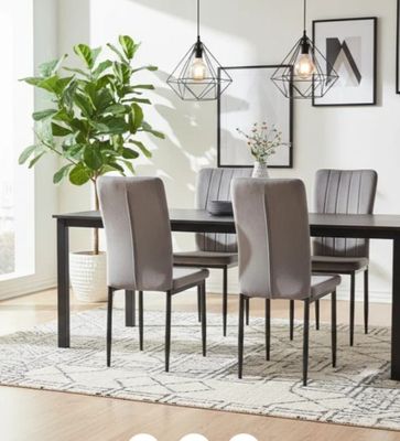 a dining room table with chairs and a plant in the corner