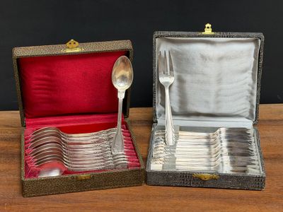 two silver spoons in a box with a spoon in it