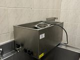 un lavabo en acier inoxydable dans une salle de bains aux murs carrelés