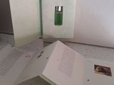 trois livres ouverts posés sur un comptoir, à côté d'un flacon de parfum