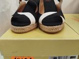 black and white wedged sandals on a box with a price tag