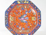 an orange and blue plate with flowers and birds on it