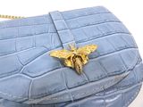 blue alligator skin purse with a gold bee broocher on it
