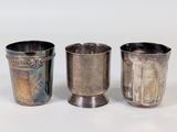 trois tasses en argent posées l'une à côté de l'autre sur une table