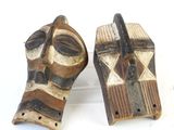 Deux masques en bois sont posés sur une surface blanche