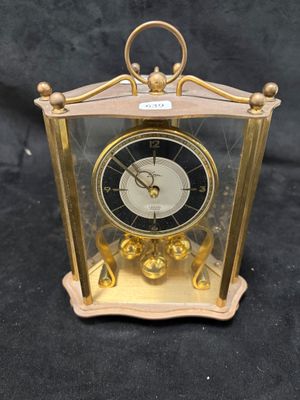 une horloge dorée dans une vitrine, sur fond noir