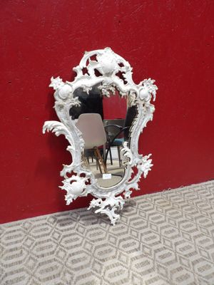 un miroir accroché au mur, à côté d'une chaise et d'une table