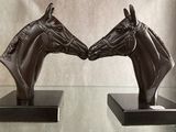 two statues of two horses facing each other on a glass table