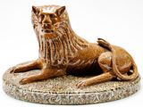 une statue représentant un lion assis sur un socle en marbre