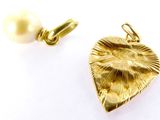 a gold heart charm with a pearl on it