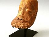 a clay mask on a black stand on a white background