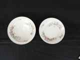 two white plates with floral designs on them sitting on a black table
