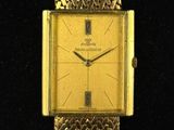 une image représentant une montre en or posée sur une surface noire