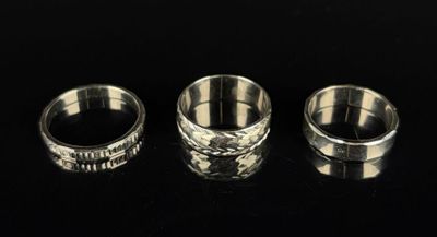 three silver rings sitting on top of a table next to each other