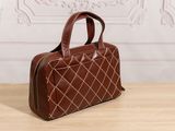 a brown purse sitting on top of a wooden table