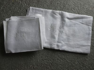 deux serviettes blanches ornées de monogrammes, posées par terre