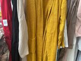 yellow cardigan sweaters are hanging on a rack in a clothing store