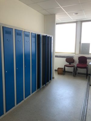 une pièce avec des casiers bleus et une chaise rouge dans un coin