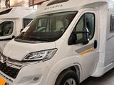deux camping-cars blancs garés dans un garage, avec une étiquette jaune à l'avant