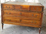 a wooden chest of drawers sitting on a brick floor