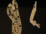 two pieces of gold chain on a black surface