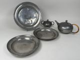 trois assiettes en argent et une théière en argent posées sur un plateau blanc