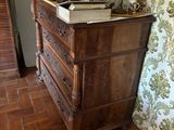 a dresser in the corner of a room with a wallpapered wall