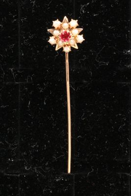 un gros plan d'une broche en forme de fleur dorée et rouge posée sur une surface en velours noir