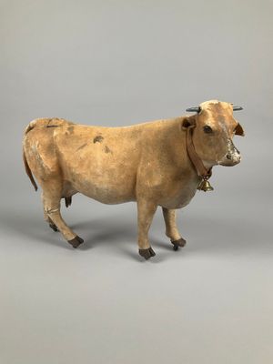 statue of a cow with a bell on a gray background