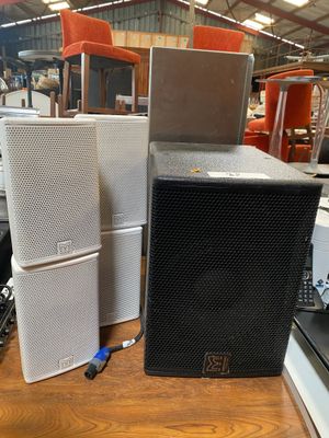 many different speakers sitting on a table in a warehouse