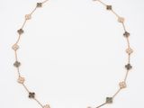 a gold necklace with green stones on a white background